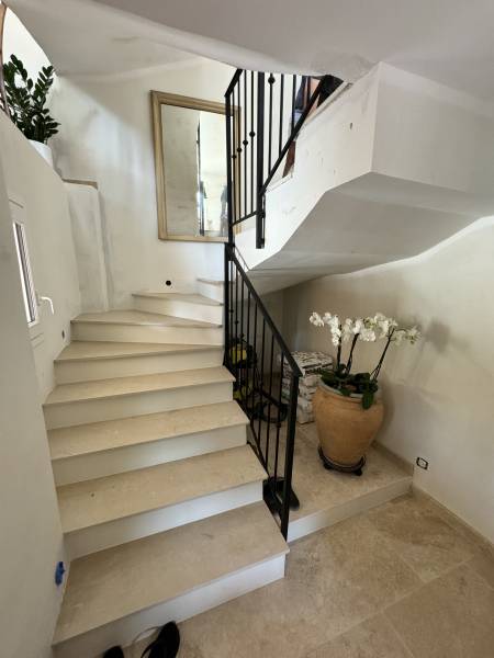 Escalier habillé de marches en pierre de Théla avec garde-corps en fer forgé, réalisé et posé à Cannes par SUDECOR.