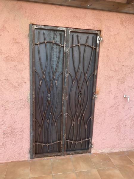 Volets en acier brut avec volutes forgées, posés sur une façade traditionnelle à Cannes – création artisanale SUDECOR.